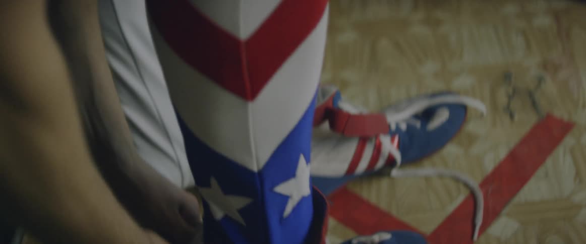 A person pulling the laces on some shoes that look like the american flag