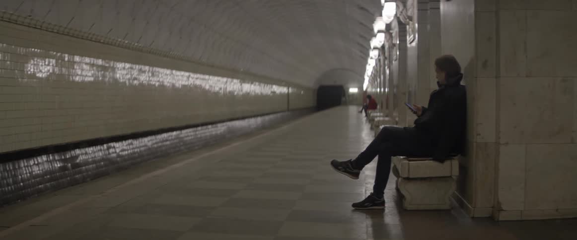 People wait on benches in a subway station