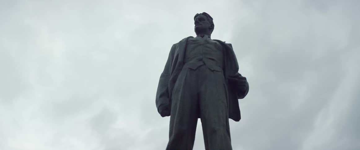 A statue of a well dressed man on a cloudy day