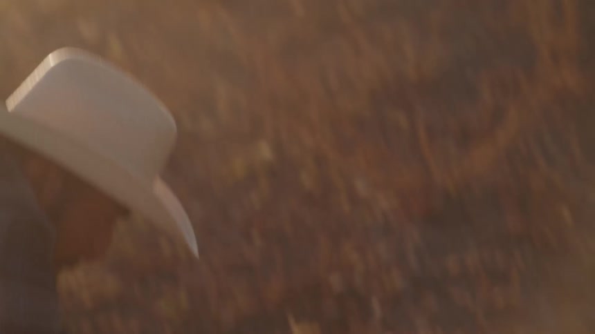 Close up of a male farmer tilling the soil on an outdoor farm with a pick axe at sunset