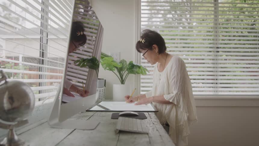 Woman writing on a project next to a computer at a desk