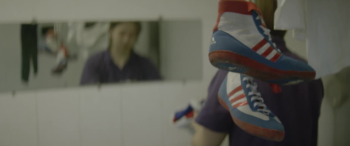 Man ringing out a flag like material with red white and blue sneakers hanging in the foreground