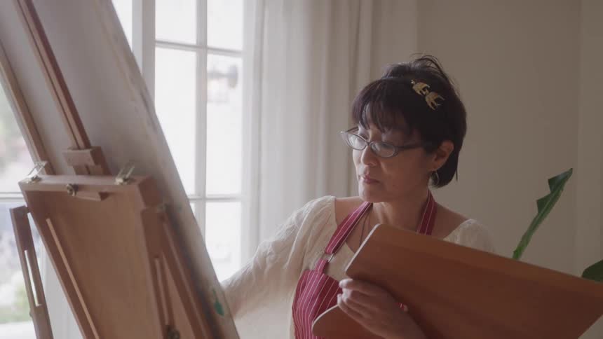 Woman painting a canvas in a room