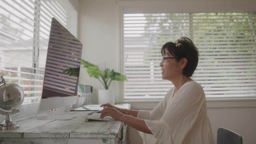 Woman sitting typing on a computer keyboard at a white table