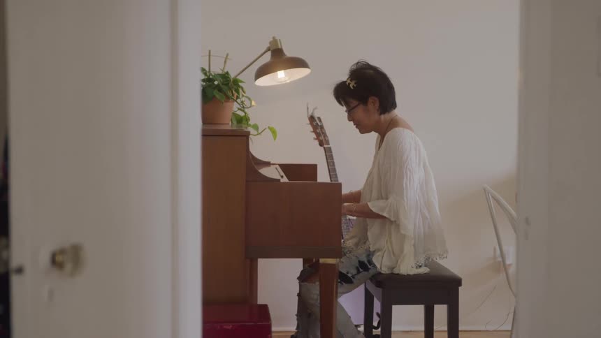 Woman sitting in a room playing the piano