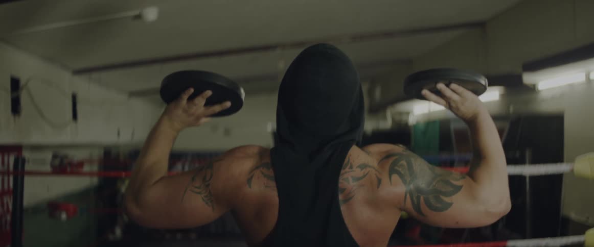 A man lifts weights inside a wrestling ring