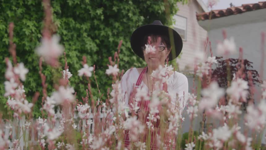 Smiling woman with black hat in a garden with white flowers