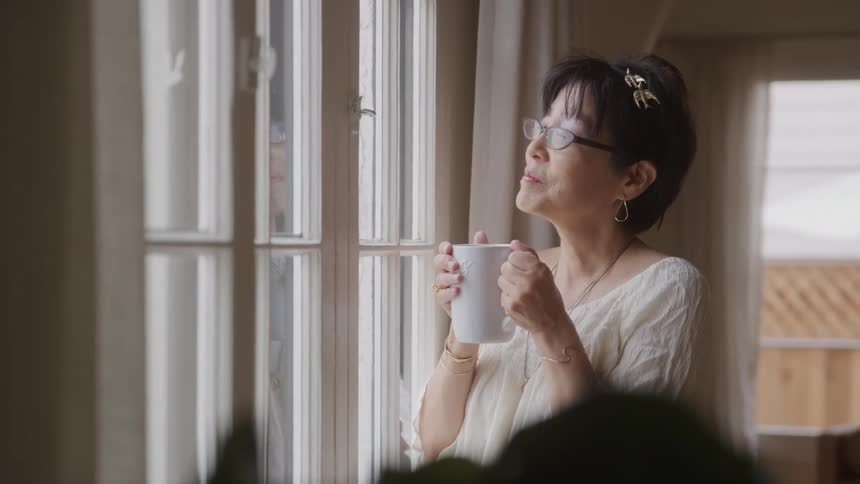 Woman drinking from a cup and looking out the window
