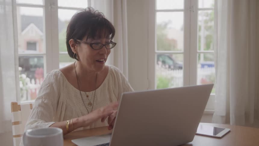 Woman sitting at a table talking in front of a laptop