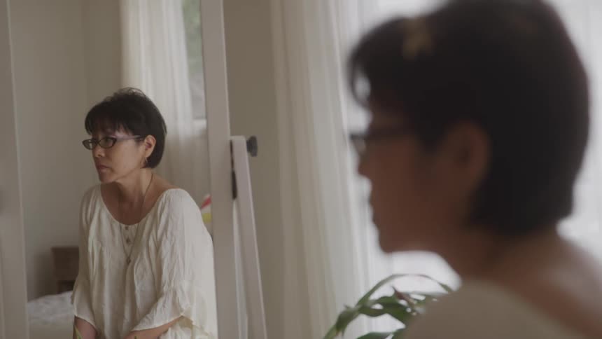 Reflection of a woman in the mirror in a room of the house