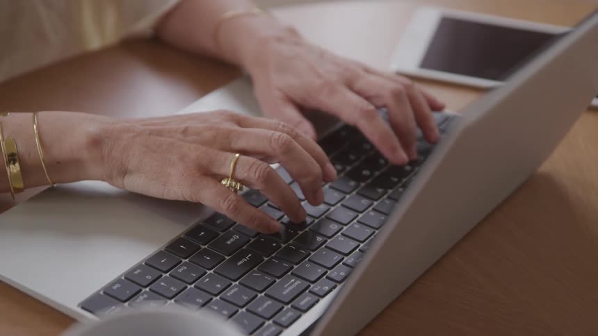 Pair of hands of a person typing on a laptop keyboard