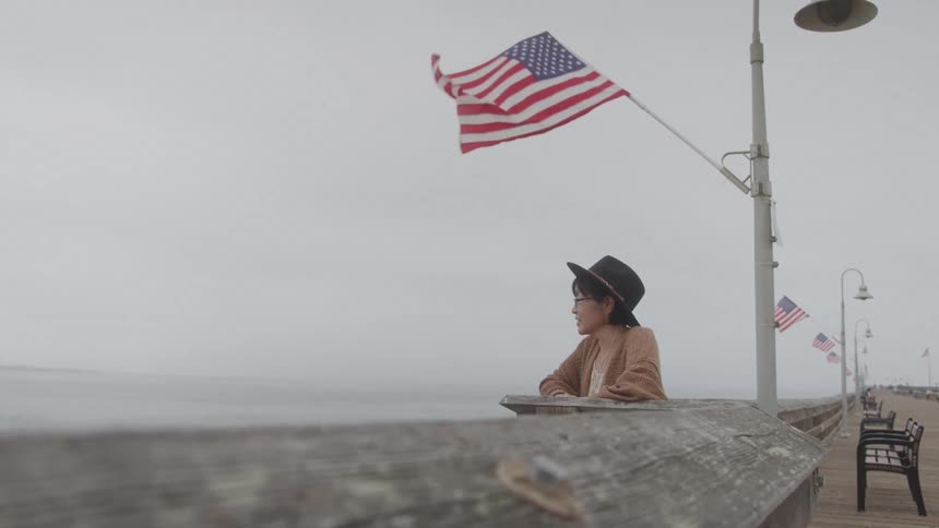 Woman in a hat on a pier enjoying the sea view on a cloudy day