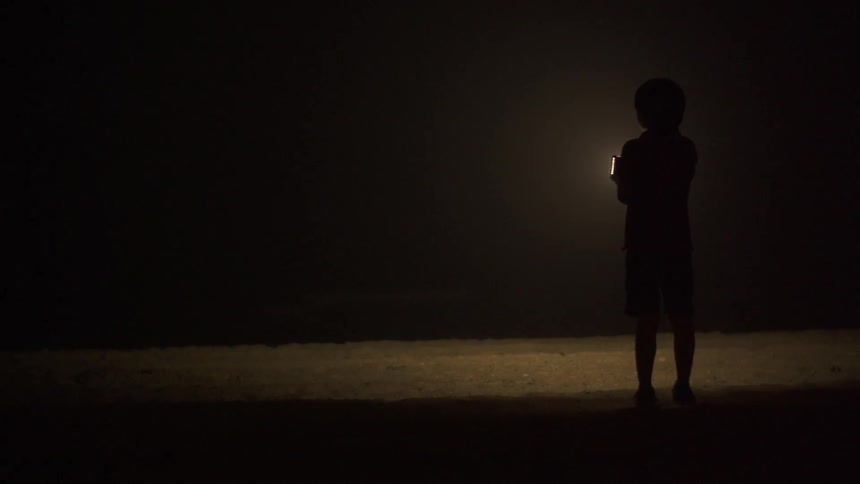 Person standing in the dark holding a glowing light