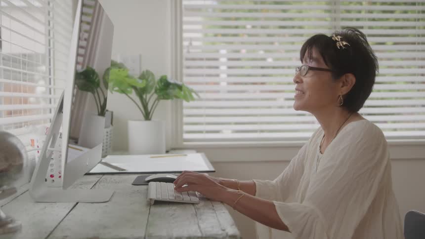 Woman sitting with a happy expression typing on a computer keyboard