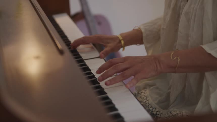 A woman is playing the piano in a well lit room