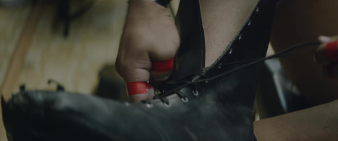 A person with tape on their fingers laces their boots