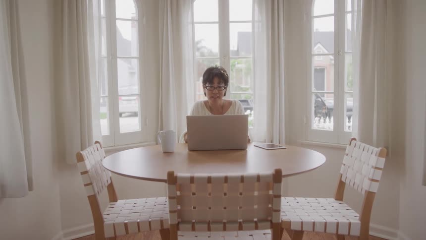 Woman sitting at a table typing on a laptop
