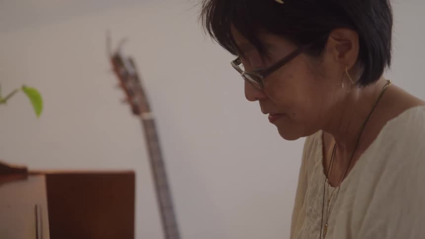 Woman looking down concentrated with a guitar in the background