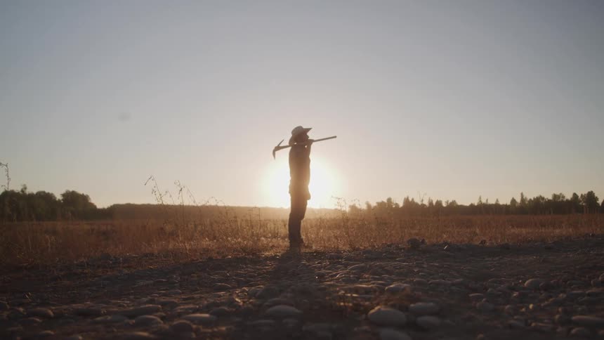 A man stands in a field with a tool