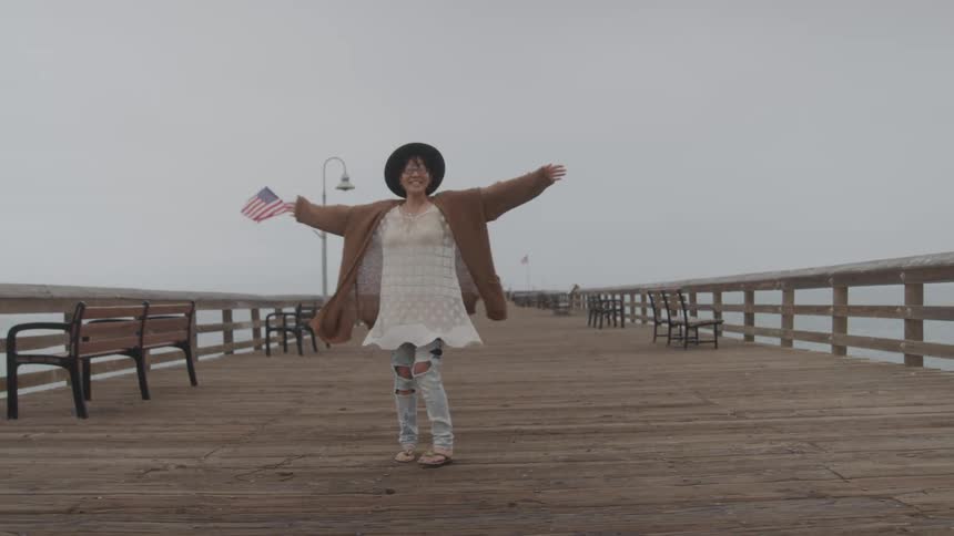 A woman twirls on a pier