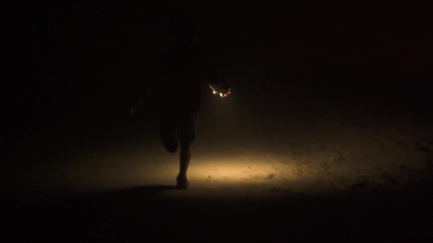 A child holding a light in his hand as he runs down a dirt road