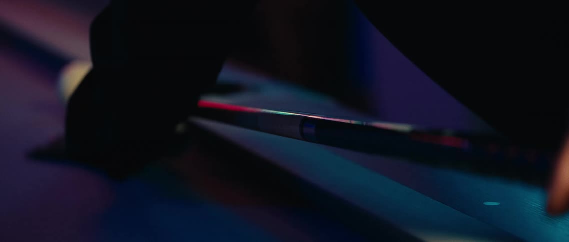 A person holding a pool stick hits the white ball with it