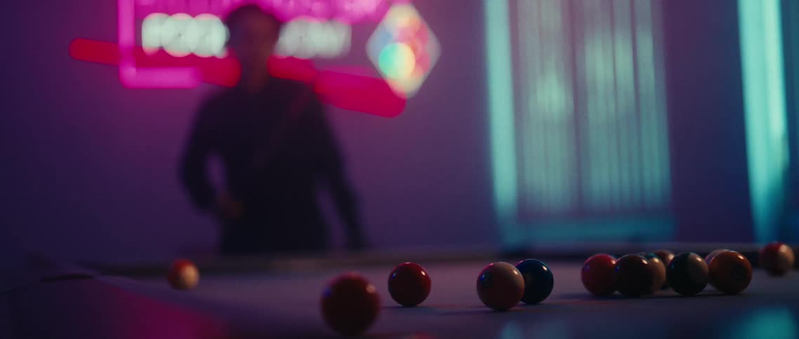 Person in a lowlit room playing pool