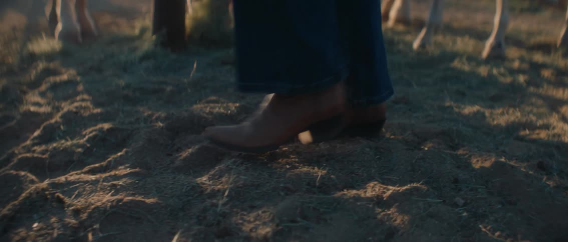 The woman is walking by the horses