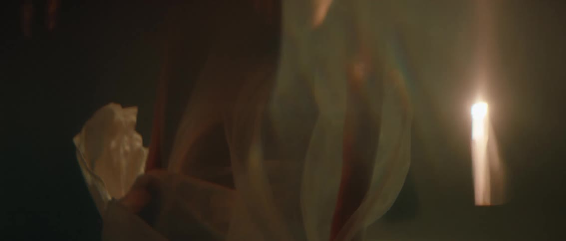A close view of a persons body is partially submerged in water with light colored fabric swirling around their arms and legs
