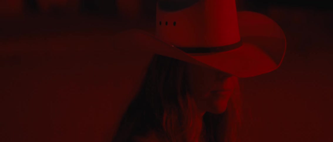Woman in white hat in an outdoor setting at night with red light