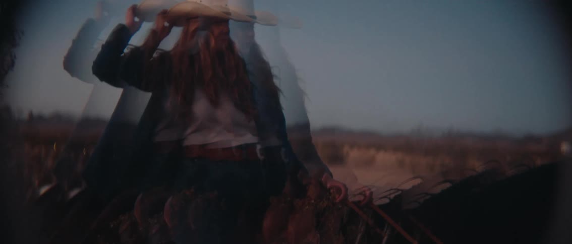 Woman on horseback taking off her white hat