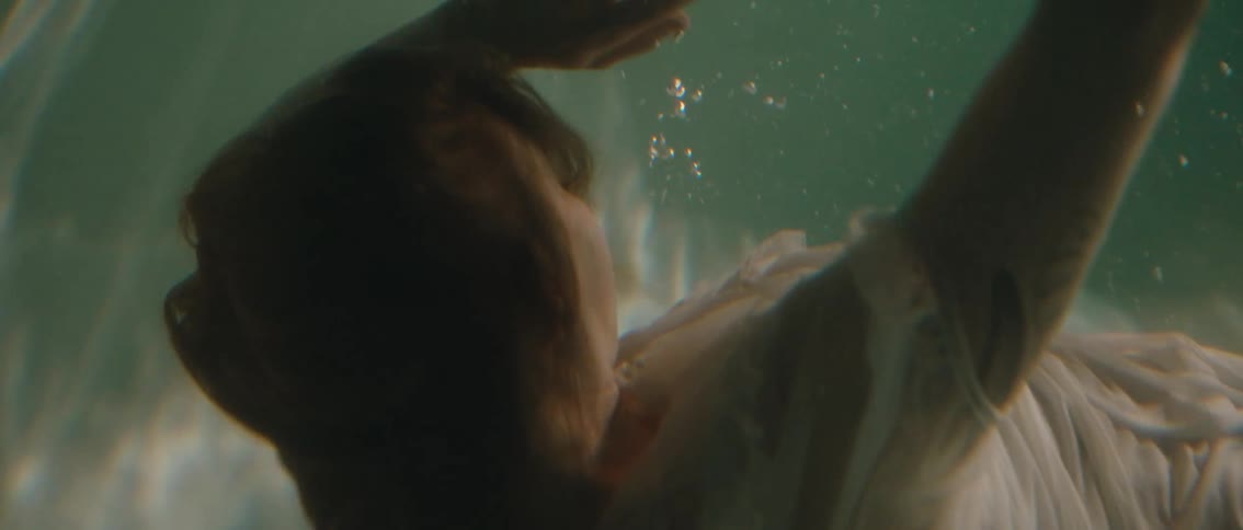 Woman in white dress submerged in a pool