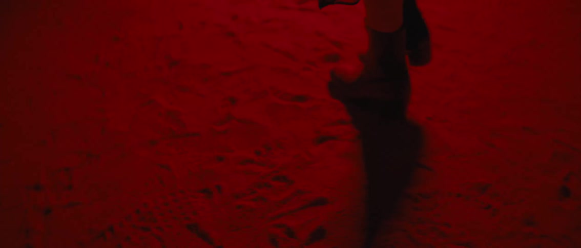 Person in boots walking outdoors over a red light at night