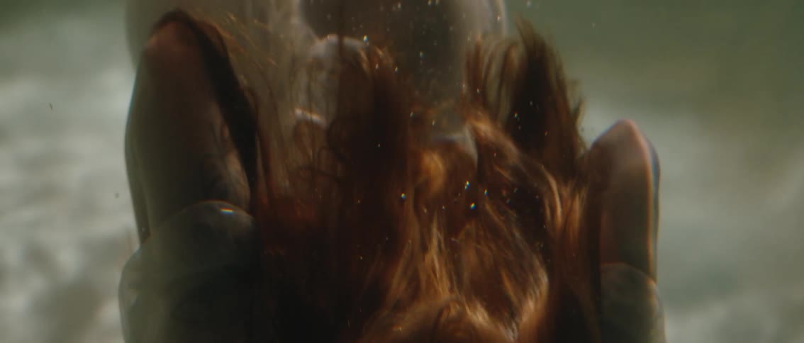 A captivating underwater closeup of a womans hair as it floats and dances with the current illuminated by shimmering light and surrounded by tiny bubbles