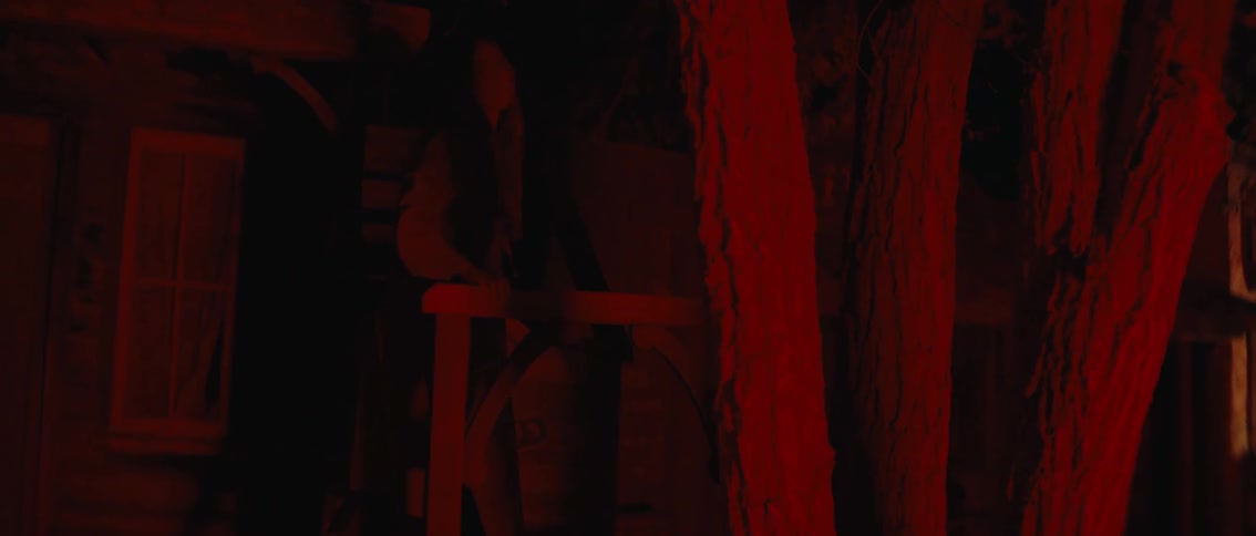 Woman with white hat walking in a western setting at night with red light