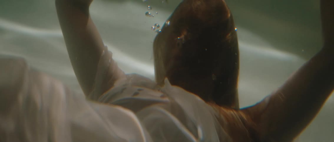 Woman in white dress submerged in pool