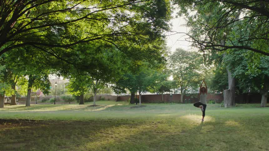 A woman does yoga poses in a park
