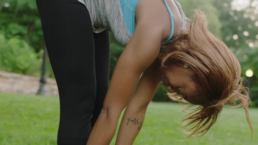 A woman bending over and stretching in the yard