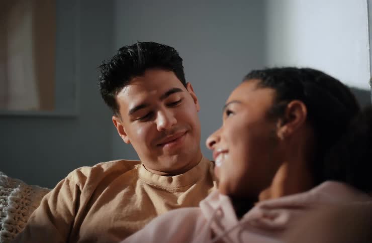 A couple sitting on a couch talking and laughing at midday in their living room
