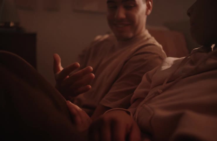 A man holding the hand of a woman as they sit on a couch talking and laughing