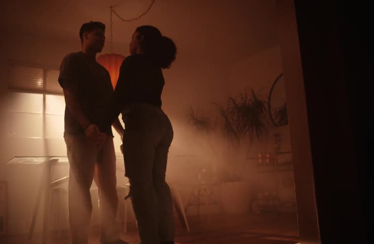 A couple dances slowly in a room with sunlight streaking through the window