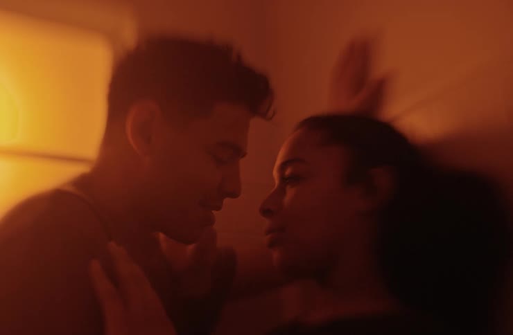 A young couple kissing each other passionately indoors while resting against the wall