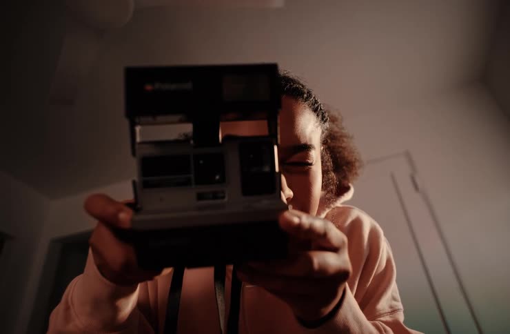 Curly haired woman taking a photograph with a vintage camera