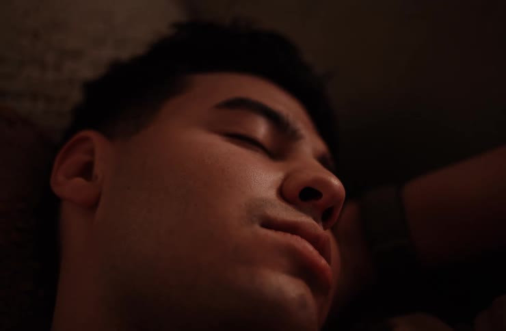 A young man sleeping indoors wearing a wristwatch