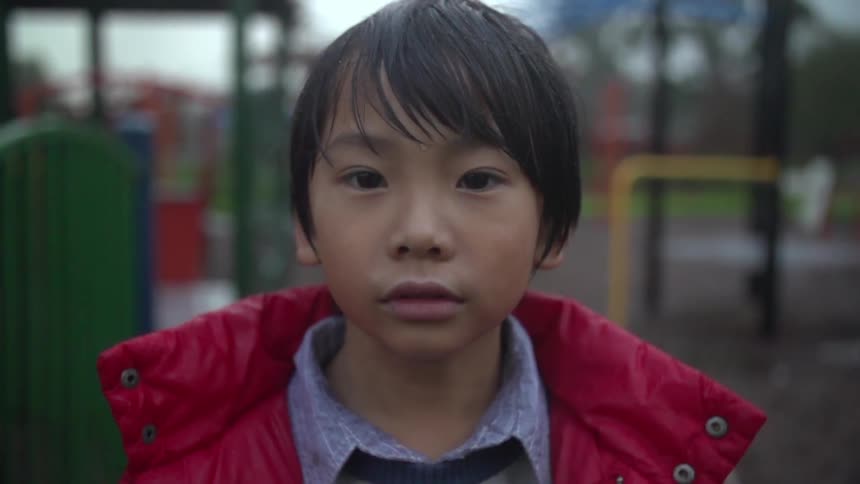 Boy standing in a park wearing a red coat