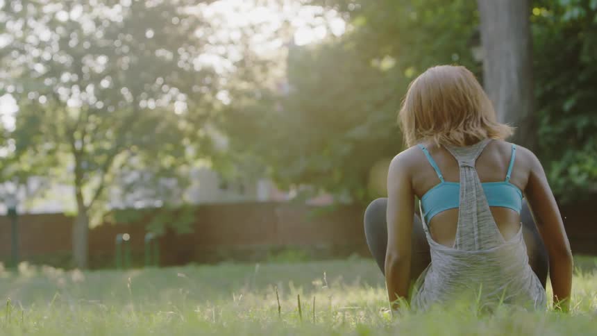 Woman sitting down in a grassy area with her legs crossed