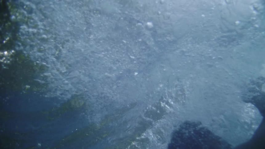 Water splashes as a person jumps in holding his nose