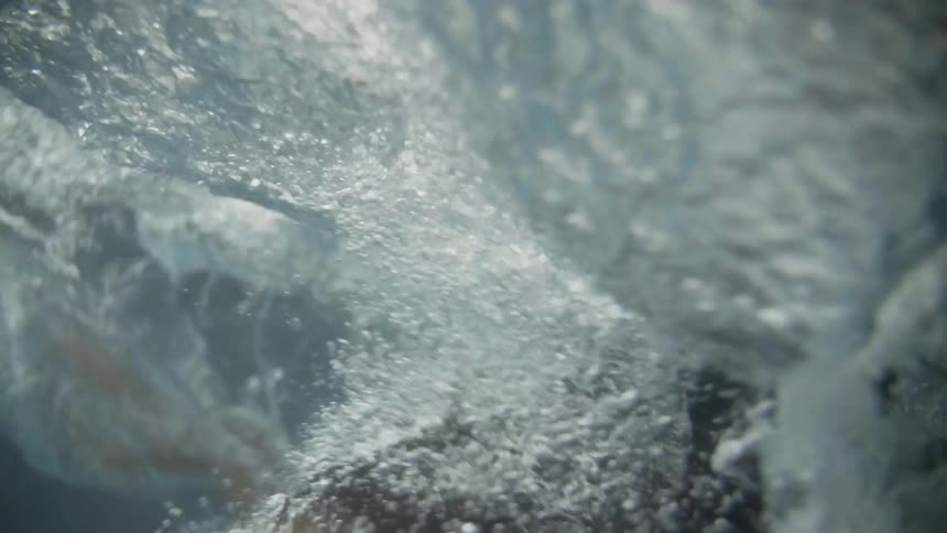 A person diving into some water and making lots of bubbles