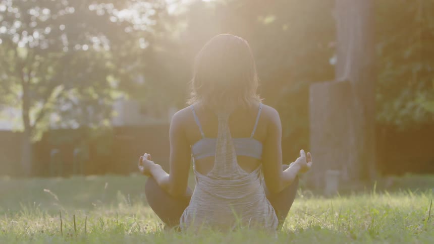 A woman is sitting in grass meditating