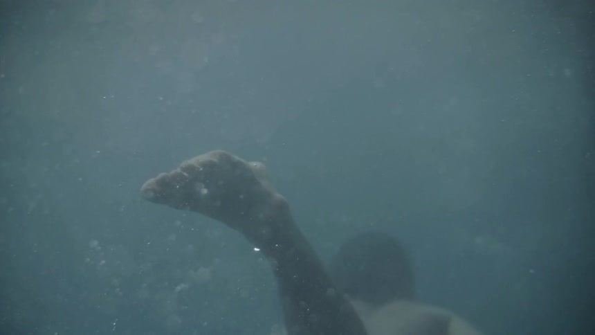 A man kicks his feet and swims underwater